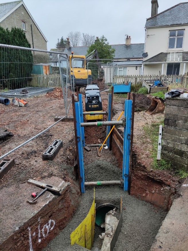 A colour photograph of flood improvement works being carried out in a trench.