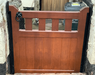 A brown  flood gate in a between stone walls in a front garden.