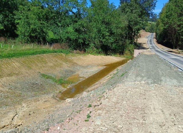 A drainage basin next to a road