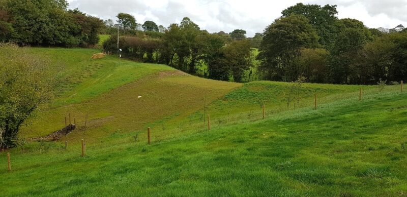 Complete bund, grass covered field with slope that makes up the bund. The outlet of the culvert is shown at the bottom of the slope