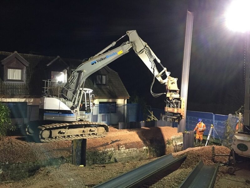 A digger and construction workers working on the construction site near the Waterloo railway line during the night