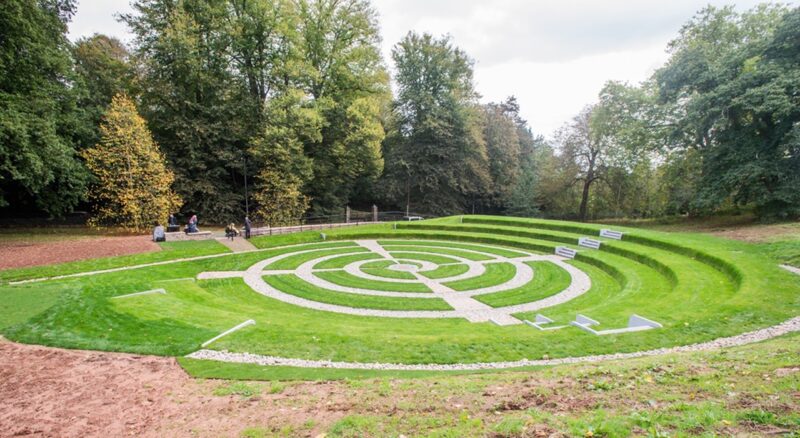 Finished flood attenuation area, grassy area with amphitheatre like step structure down to a middle open area. The attenuation crates are not visible, buried underground