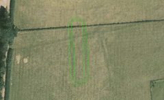 A colour aerial photograph shows a dark oblong cropmark, crossed by a straight field boundary.