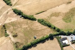 A colour aerial photograph showing dark cropmarks of a multiple-ditched enclosure.