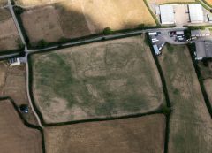 A colour aerial photograph showing dark cropmarks of ditched enclosures.