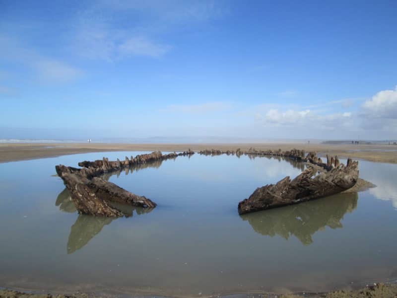 The timbers of a wreck on a beach, partially submerged in water