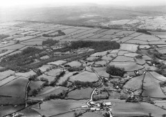 A black and white aerial photograph of the farmed landscape of Stockland reflects several phases of enclosure: prehistoric enclosures such as Stockland Little Castle (circular field centre right); irregular small medieval fields in the foreground; and distinctive large rectangular fields of nineteenth-century date on Stockland Hill.