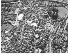 Totnes from the air in 1990. The town’s development can be seen in its layout. The circuit of the Saxon walls can be seen as well as the Norman castle that was built on top of earlier residential properties. The medieval church dominates much of the town centre and the market square is also prominent. Medieval tenement strips (‘burgage’ plots) can be seen on either side of the main street, inside and outside the walls. Early 20th century suburban terraces are set out in ranks on the slopes below the castle (Photo: Frances Griffith, Devon County Council).