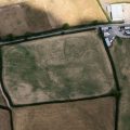 A colour aerial photograph showing dark cropmarks of ditched enclosures.