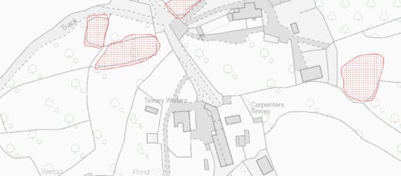 A greyscale map overlain by transcriptions of the earthwork banks, mapped as irregular areas to the north, east and west of the modern settlement.