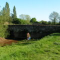 A colour photograph of a stone bridge with several arches, from the side.