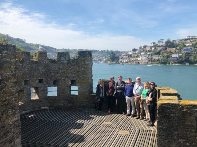 A group of people standing on the top of a castle fort, overlooking the sea