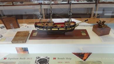 A wooden model of a ship, in a glass display container