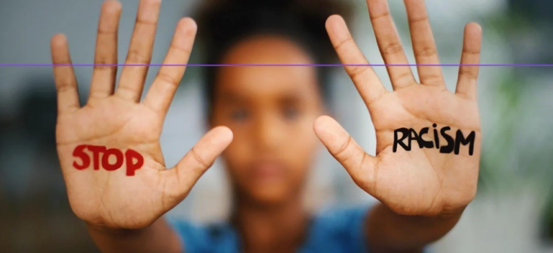 person holding out palms of hands with words stop and racism written on them