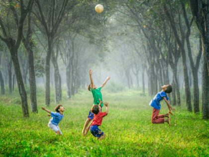 image of 4 children playing with a ball in a wood