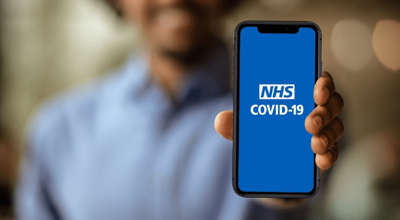 Person holding up their mobile phone to the camera, with the NHS Covid-19 app on the screen