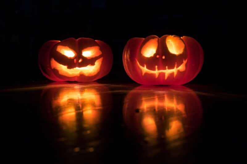 two carved pumpkins lit in the dark
