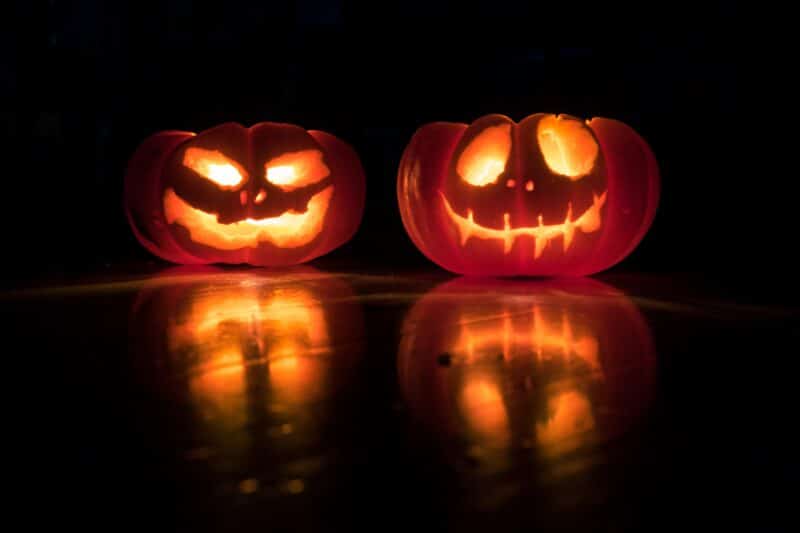 two carved pumpkins lit in the dark