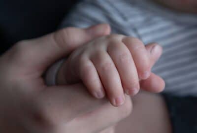 close up image of mother's hand holding baby's hand
