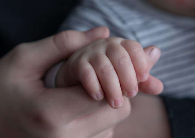 close up image of mother's hand holding baby's hand