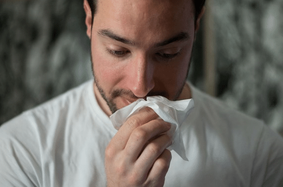 man wiping his nose with a tissue