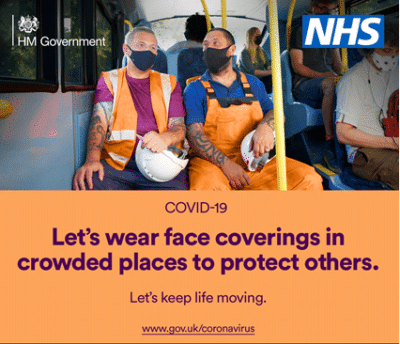 Two people sat on a bus wearing face coverings