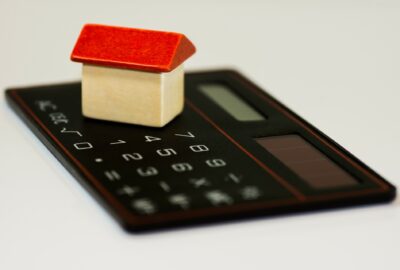 a calculator with a model house by it, indicating household bills