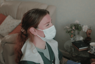 care worker, wearing a face covering, laughing with a person she cares for