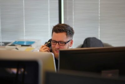 A young man working at his desk and talking on the telephone