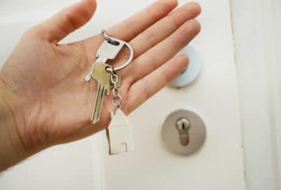 hand, holding a bunch of keys in front of a door