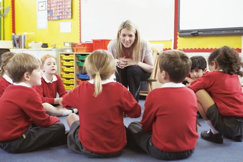 teacher talking to school children sat on floor