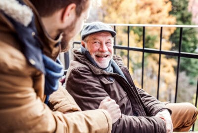 Two men, one younger and one older, chatting and laughing together