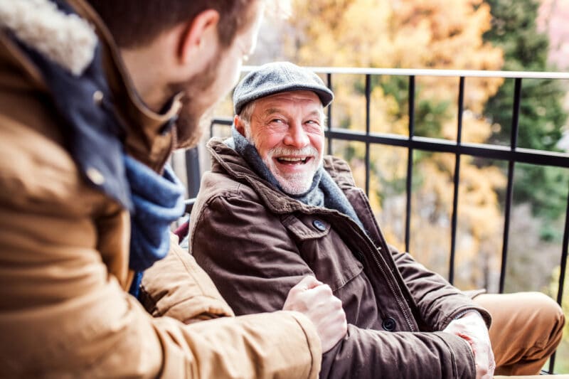 Two men, one younger and one older, chatting and laughing together