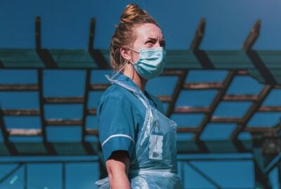 a nurse, outside wearing a face covering