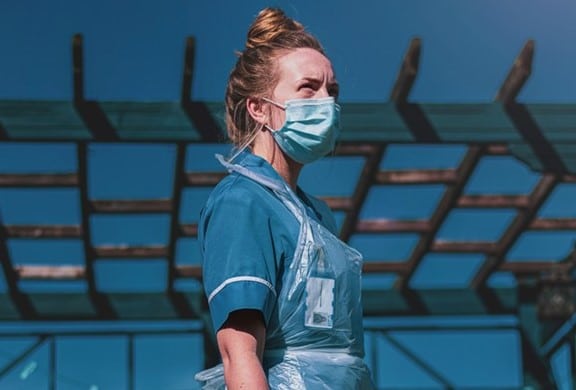 a nurse, outside wearing a face covering