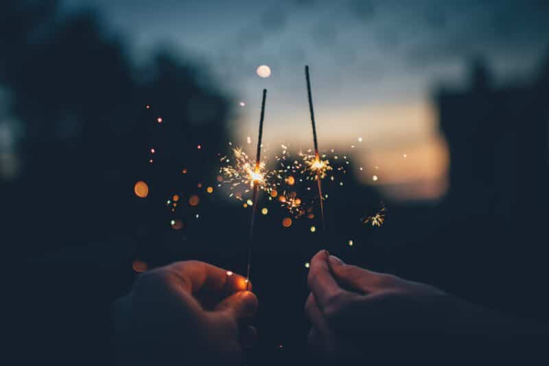 two people holding sparklers in the dark