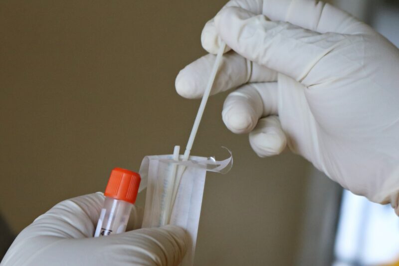 surgical gloved hands holding PCR test