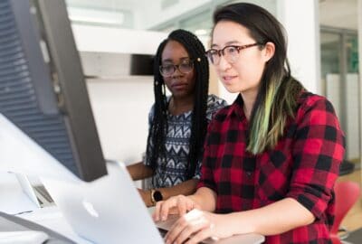 Two people working together looking at a computer monitor