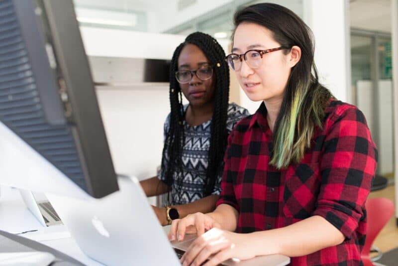 Two people working together looking at a computer monitor