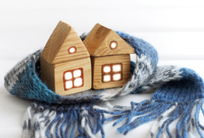 Two small model houses made of wood, huddled together with a scarf around them