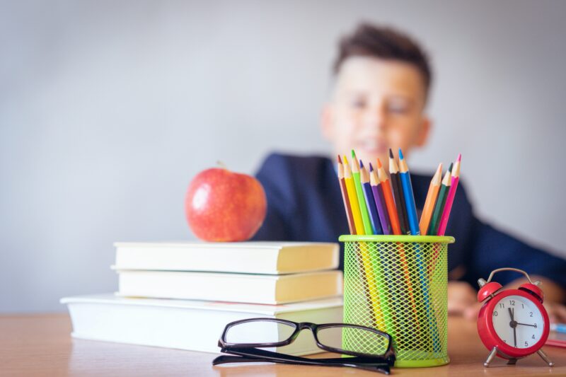 boy sat at his desk with books and pencils