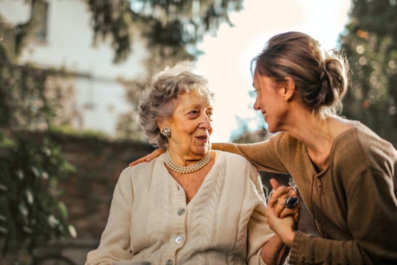 Grown up daughter visiting her elderly mother in the garden at a care home