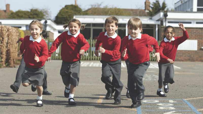 Primary school age children running across a playground