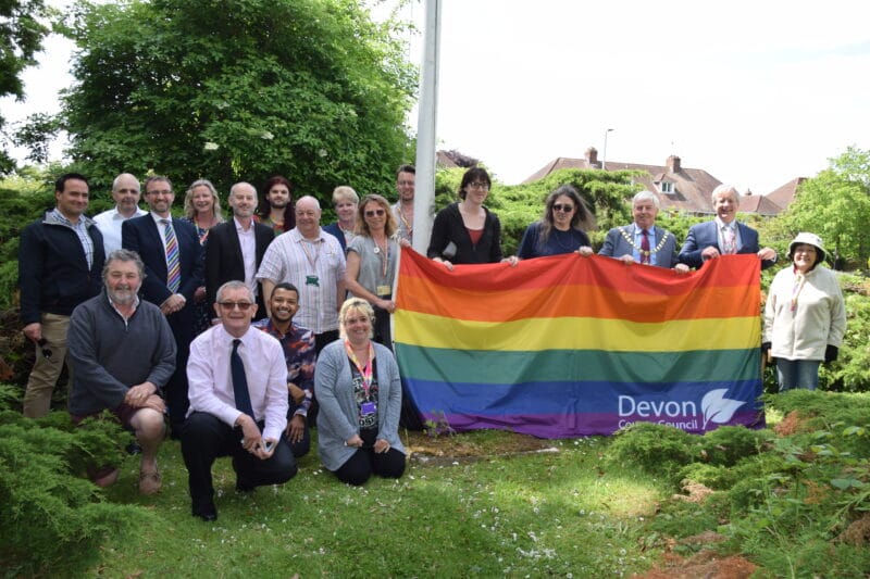 A group of people, including the Chairman of Devon County Council and Chief Executive, raising the Pride Exeter flag at County Hall this lunchtime