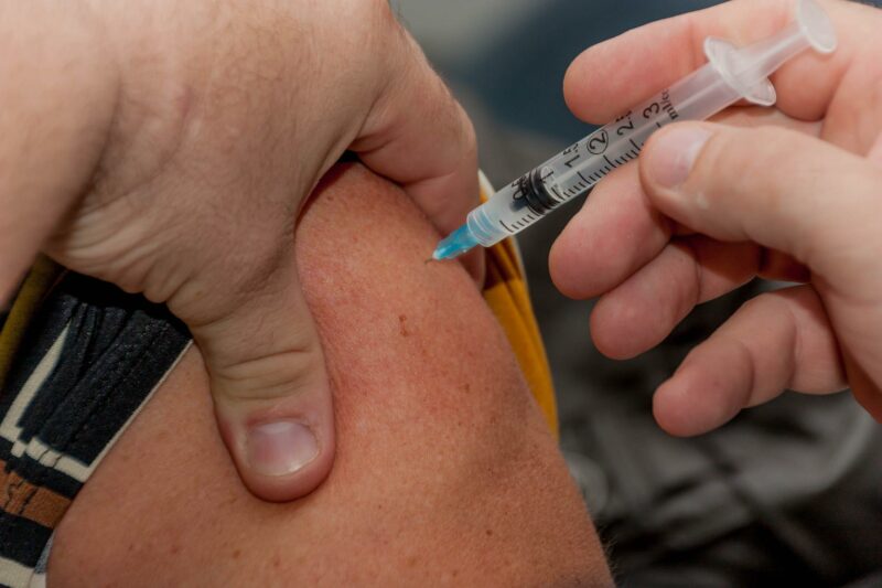 A person receiving a vaccination into their upper arm