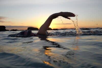 swimmers swimming in the sea at sunset