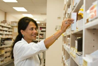 A pharmacist reaching for something off a shelf
