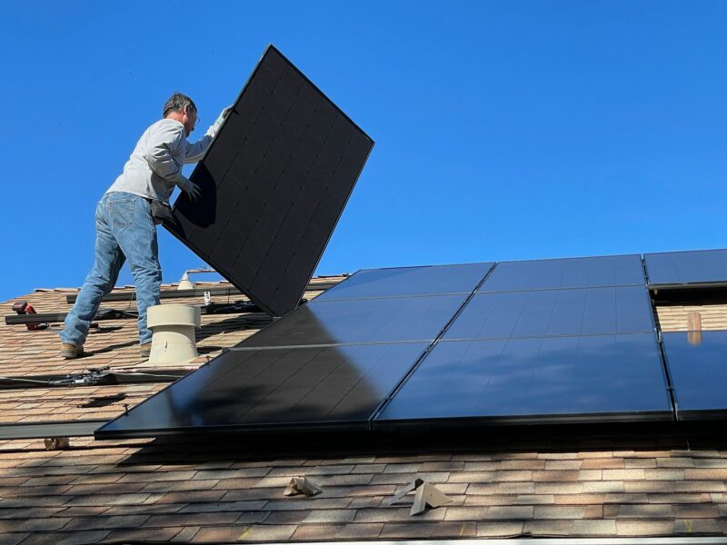 A man fitting solar panels to a roof