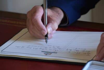 A hand signing the Book of Condolence