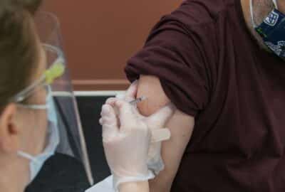 A older person receiving a vaccination into his upper arm